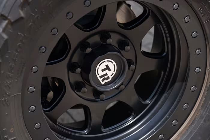 Black wheel with a branded center cap and perimeter bolts — photo 15 of 23